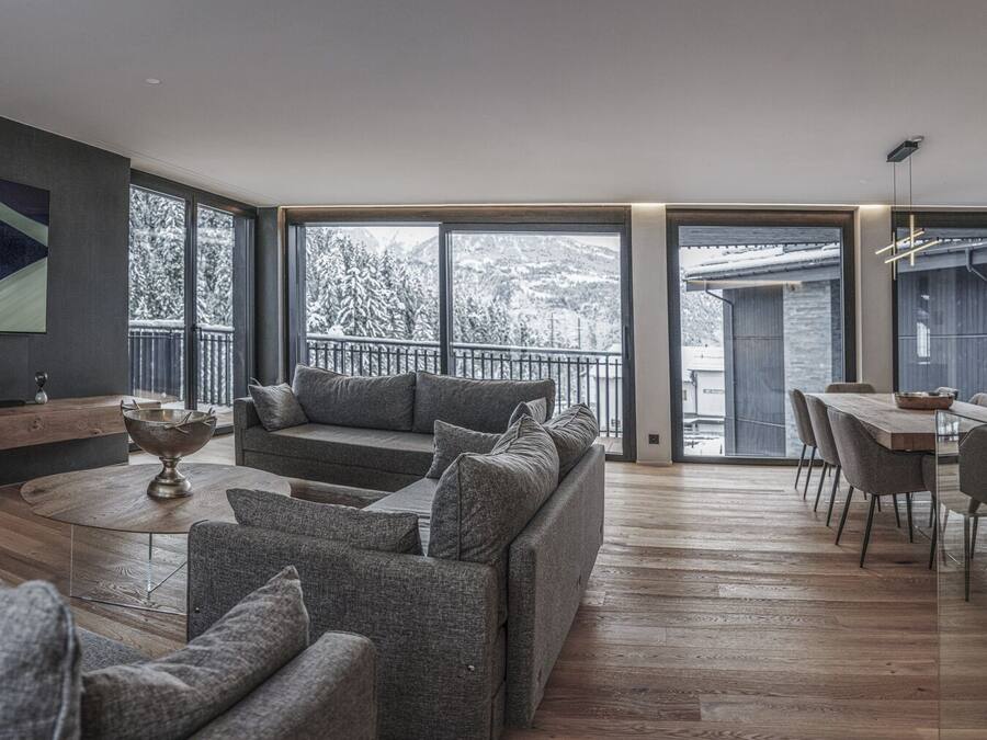 A modern living room with a sofa, a coffee table, and a dining area with a table and chairs.