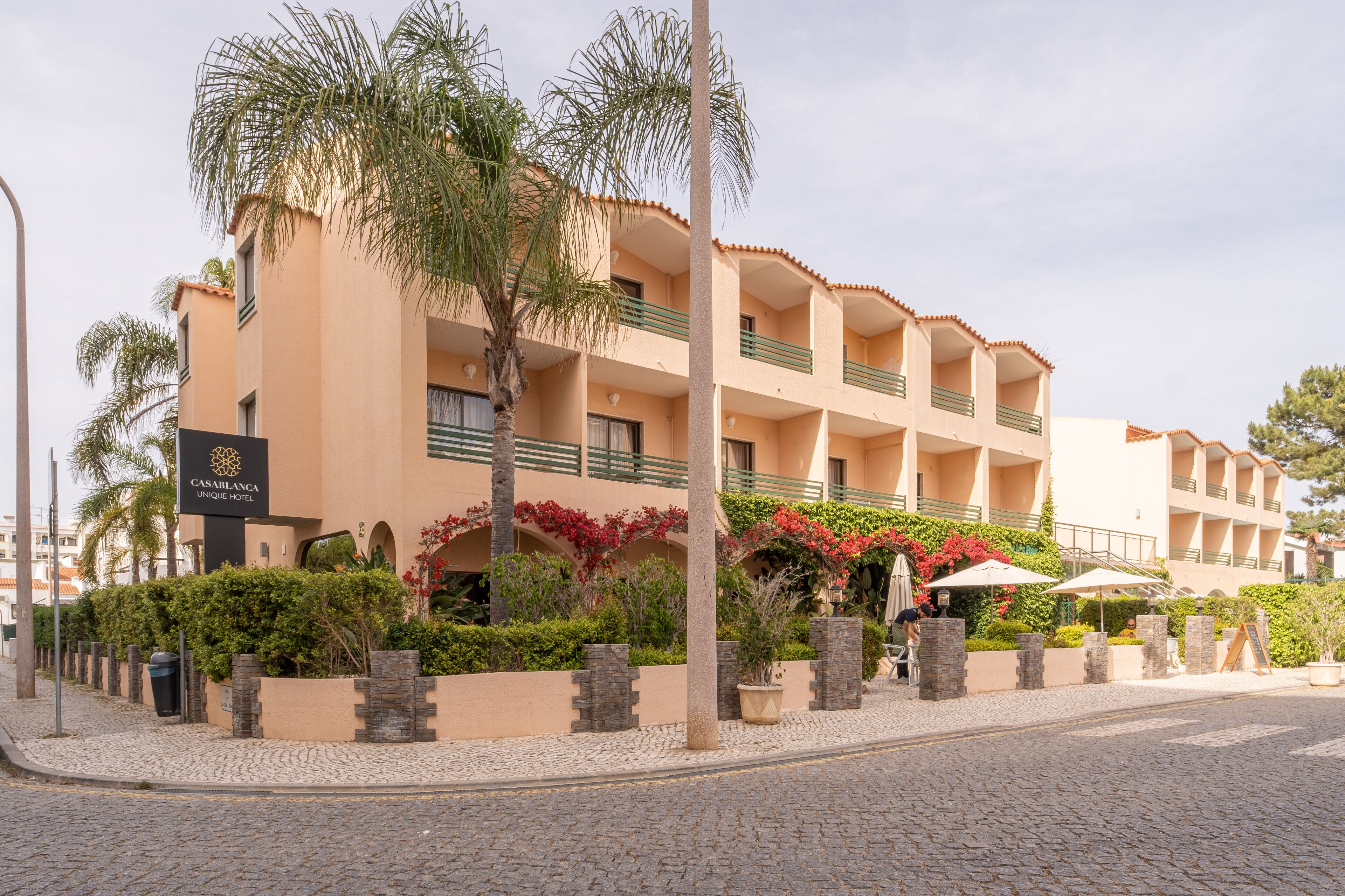 A hotel with multiple balconies, a palm tree, and a sign reading "CASABLANCA UNIQUE HOTEL".