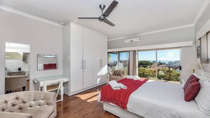 Camera d'albergo moderna con un letto grande, una scrivania, una sedia e un balcone con vista sulla città.