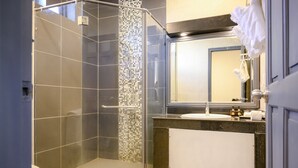 Un bagno moderno con doccia vetro, un backsplash in mosaico piastrellato, un lavabo con specchio sopra e un porta asciugamani.