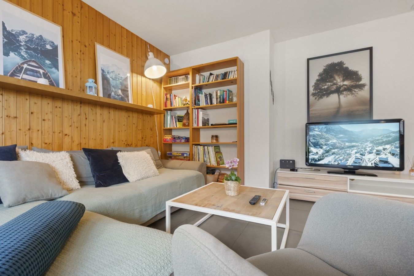 Uma sala de estar moderna com sofá, mesa de centro, estante e televisão.
