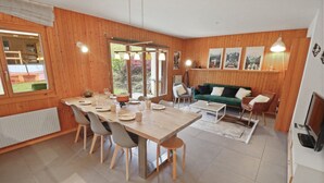 A cozy room with a wooden interior, a dining table with chairs, a sofa, and a television.