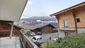A wooden chalet with a balcony overlooking a mountain landscape.