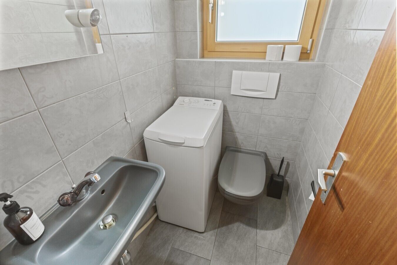 A compact bathroom with a sink, toilet, and washing machine.