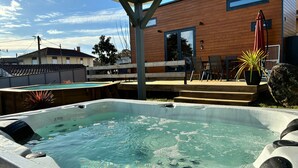 A hot tub with a wooden deck and a house in the background.