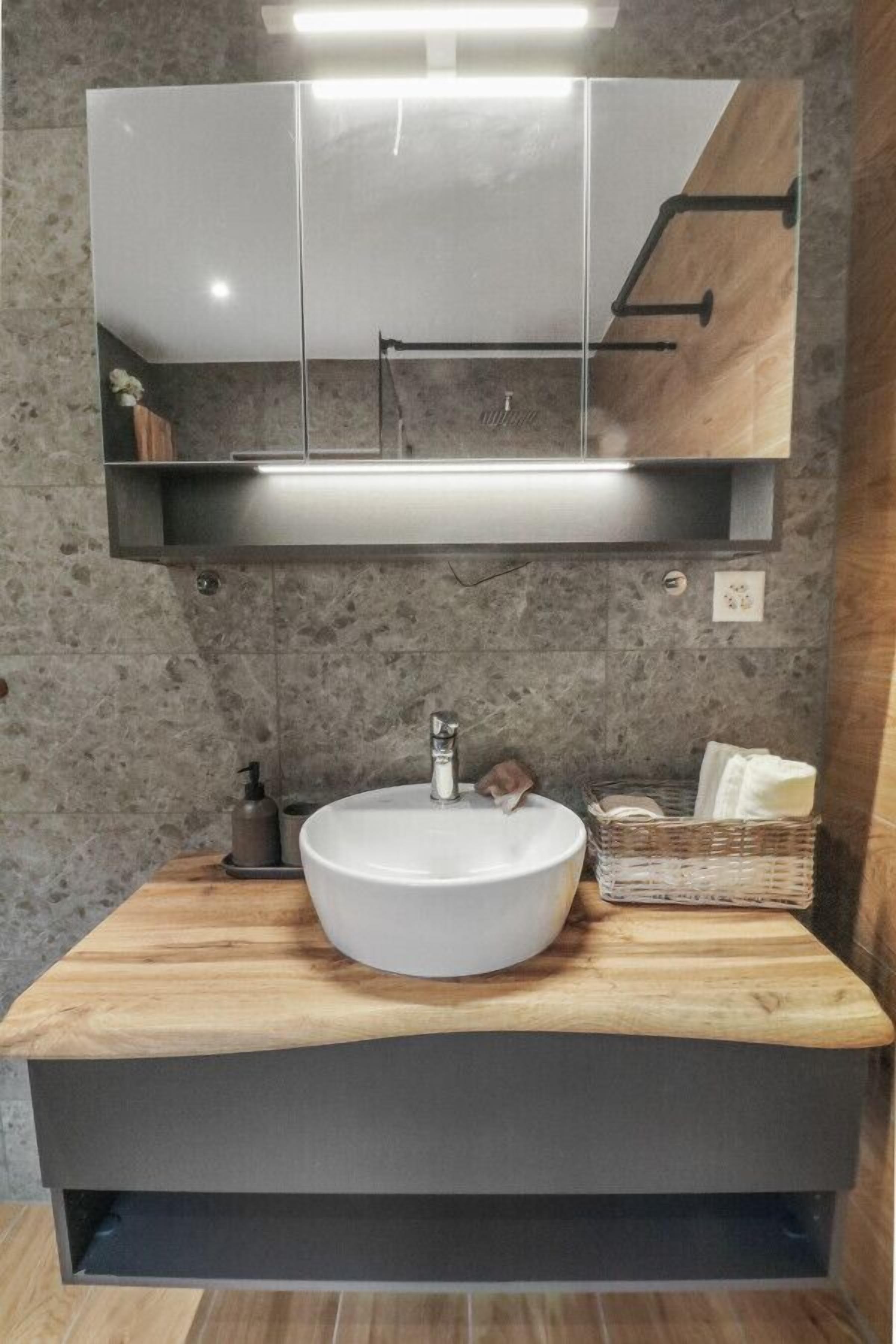 A modern bathroom with a large white sink, wooden countertop, and a mirror above.