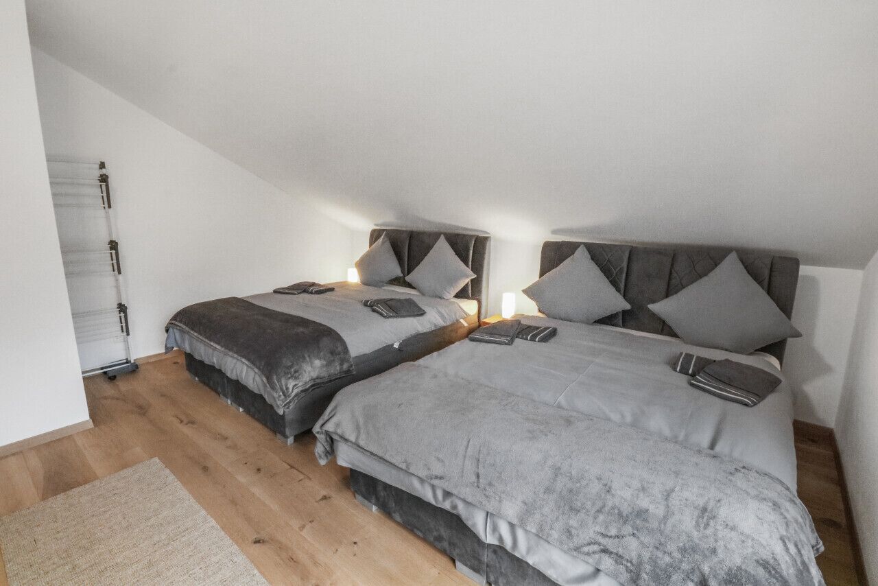 Een slaapkamer met twee bedden, elk met hoofdbord, nachtkastjes en een vloerkleed.