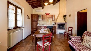 Une cuisine chaleureuse avec des meubles en bois, une table à manger avec des chaises et une cheminée.