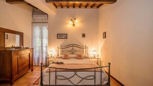 Quarto com estrutura de cama em metal, cómoda de madeira e um espelho grande.