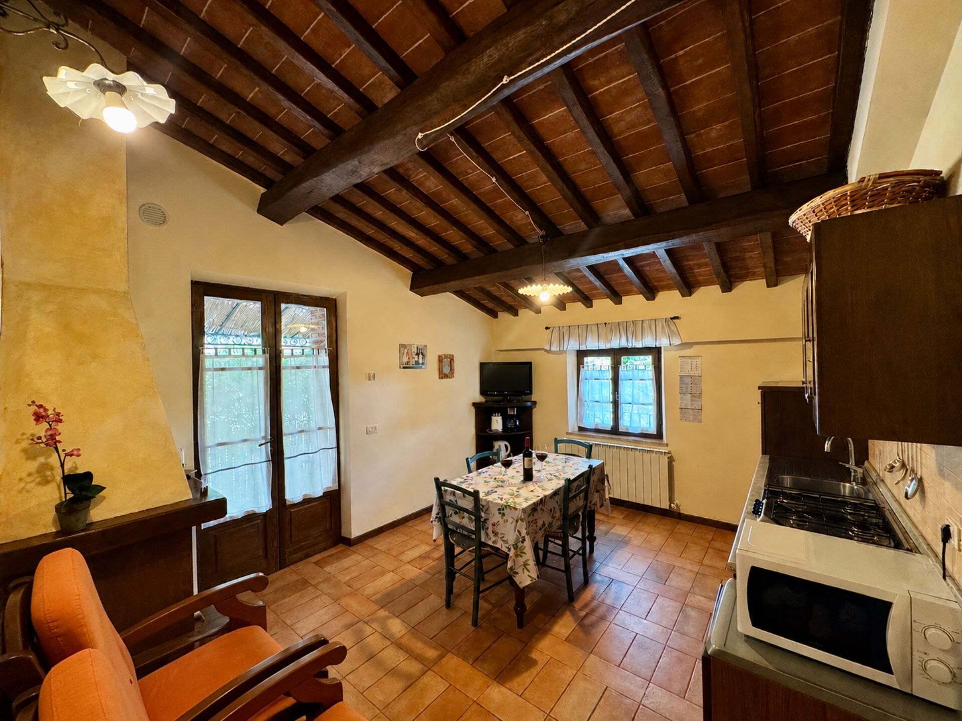 Una cocina acogedora con comedor, vigas de madera, estufa y una mesa dispuesta para dos.