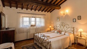 Una camera da letto con un letto, un comodino, tende e un termosifone.