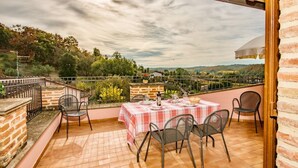 A terrace with a table set for dining, surrounded by chairs, overlooking a scenic landscape. - Agriturismo Case Graziani - Palazzo 2 (Citta della Pieve)
