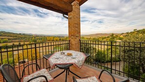 Un balcone con tavolo e sedie, affacciato su un panorama suggestivo.