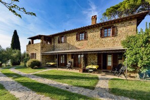 A stone building with a covered patio, outdoor seating, and a stone pathway.