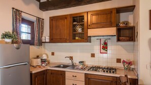 A kitchen with wooden cabinets, a gas stove, a sink, and a refrigerator. - Agriturismo Malagronda - Cipresso (Citta della Pieve)