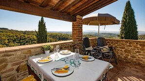 An outdoor dining area with a table set for two, overlooking a scenic landscape.