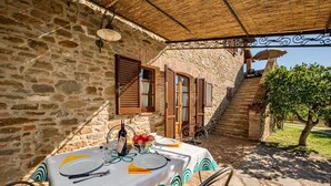 An outdoor dining area with a stone wall, wooden shutters, and a table set for two. - Agriturismo Malagronda - Quercia (Citta della Pieve)