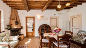 A cozy living room with a fireplace, wooden furniture, and a dining area with a table and chairs. - Agriturismo Malagronda - Quercia (Citta della Pieve)