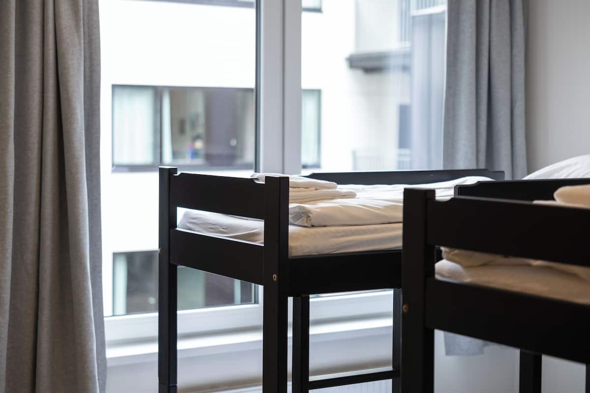 Una habitación con cama, ventana y cortinas.