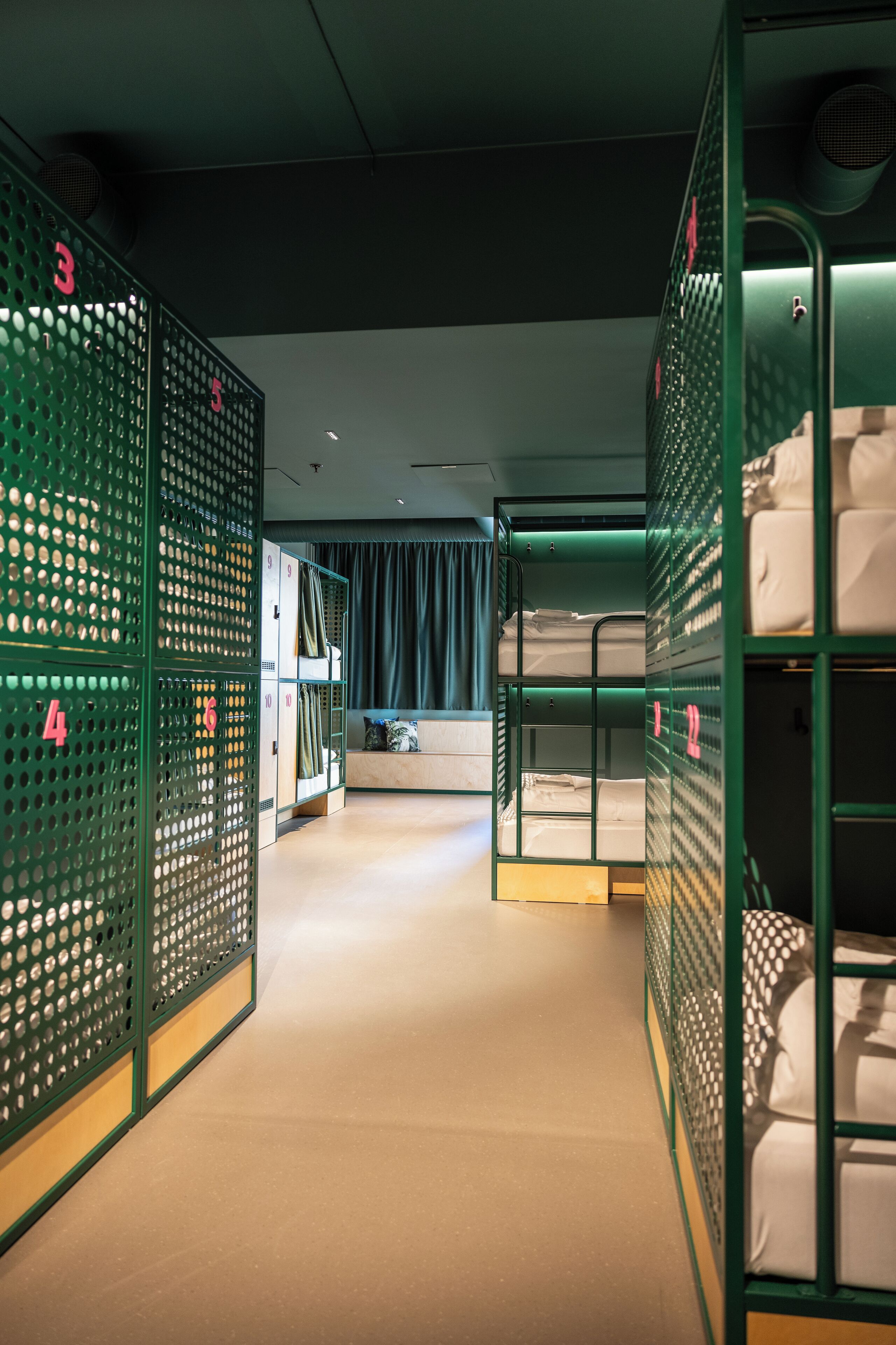 A corridor with bunk beds and lockers, each marked with numbers.