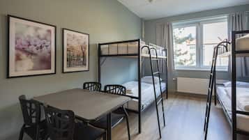 Un dormitorio con literas, una mesa, sillas y cuadros en la pared.