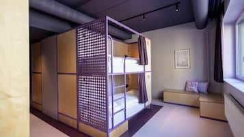 A modern, multi-level bunk bed room with a wooden finish, a seating area, and a window with curtains.