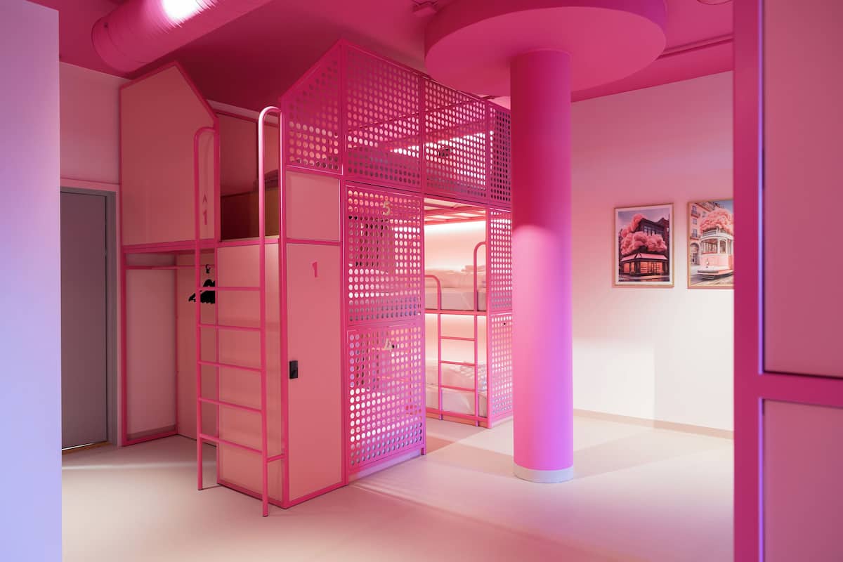 Una habitación con decoración rosa, con literas, una escalera y cuadros en la pared.