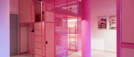 A pink-themed room with bunk beds, a ladder, and framed pictures on the wall.