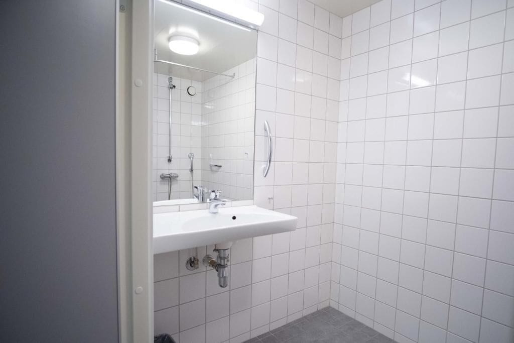 A bathroom with a white sink, mirror, and shower.