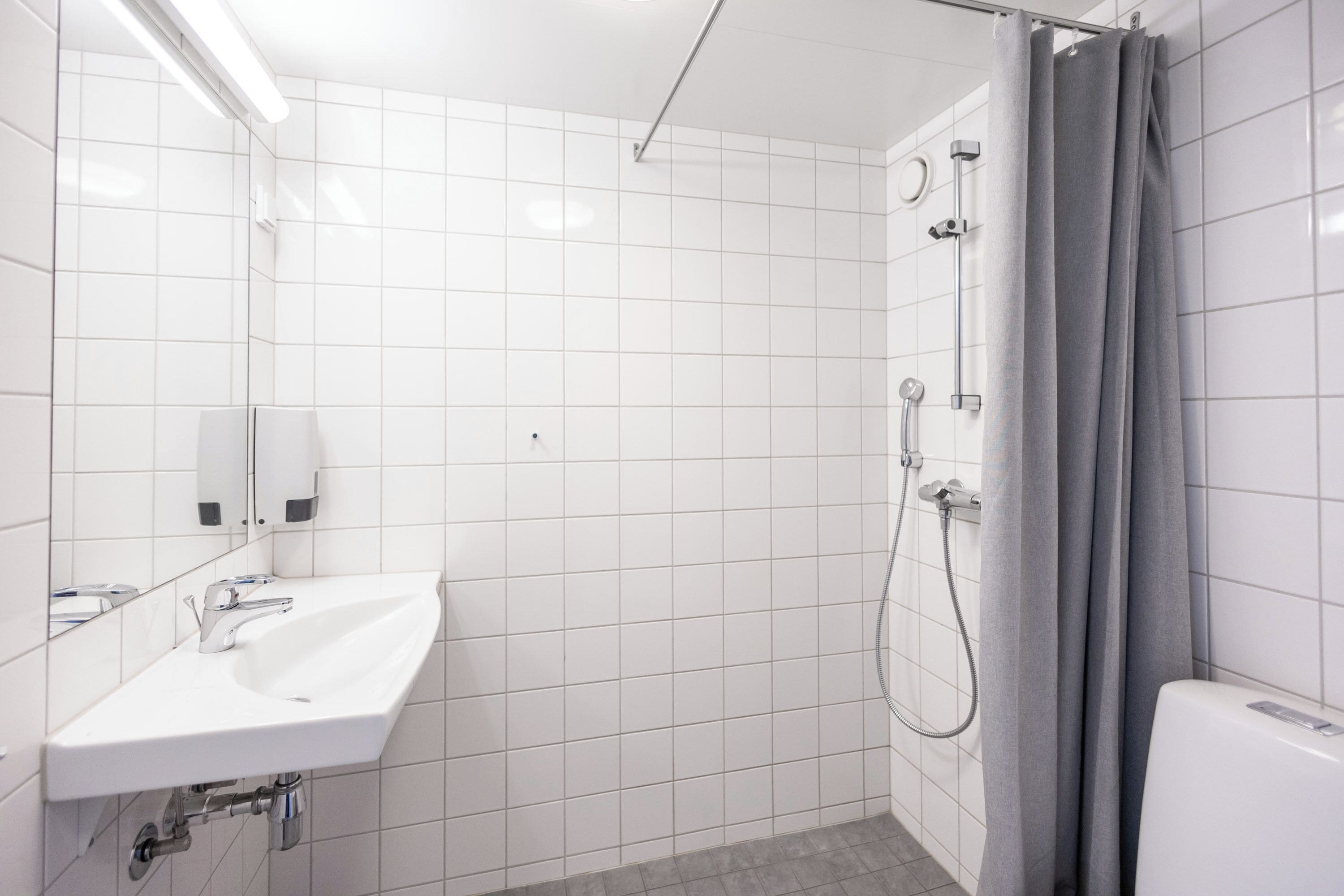 A bathroom with a white sink, mirror, and shower.