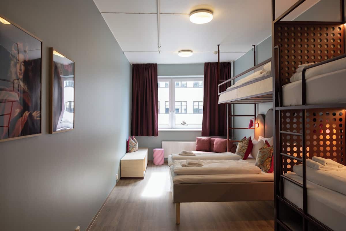 Una habitación con literas, un escritorio, una ventana con cortinas y una obra de arte en la pared.