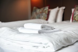 A neatly made bed with white linens and a folded towel.