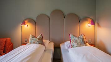 Habitación de hotel con dos camas, cabecero de diseño único y lámparas fijadas a la pared.