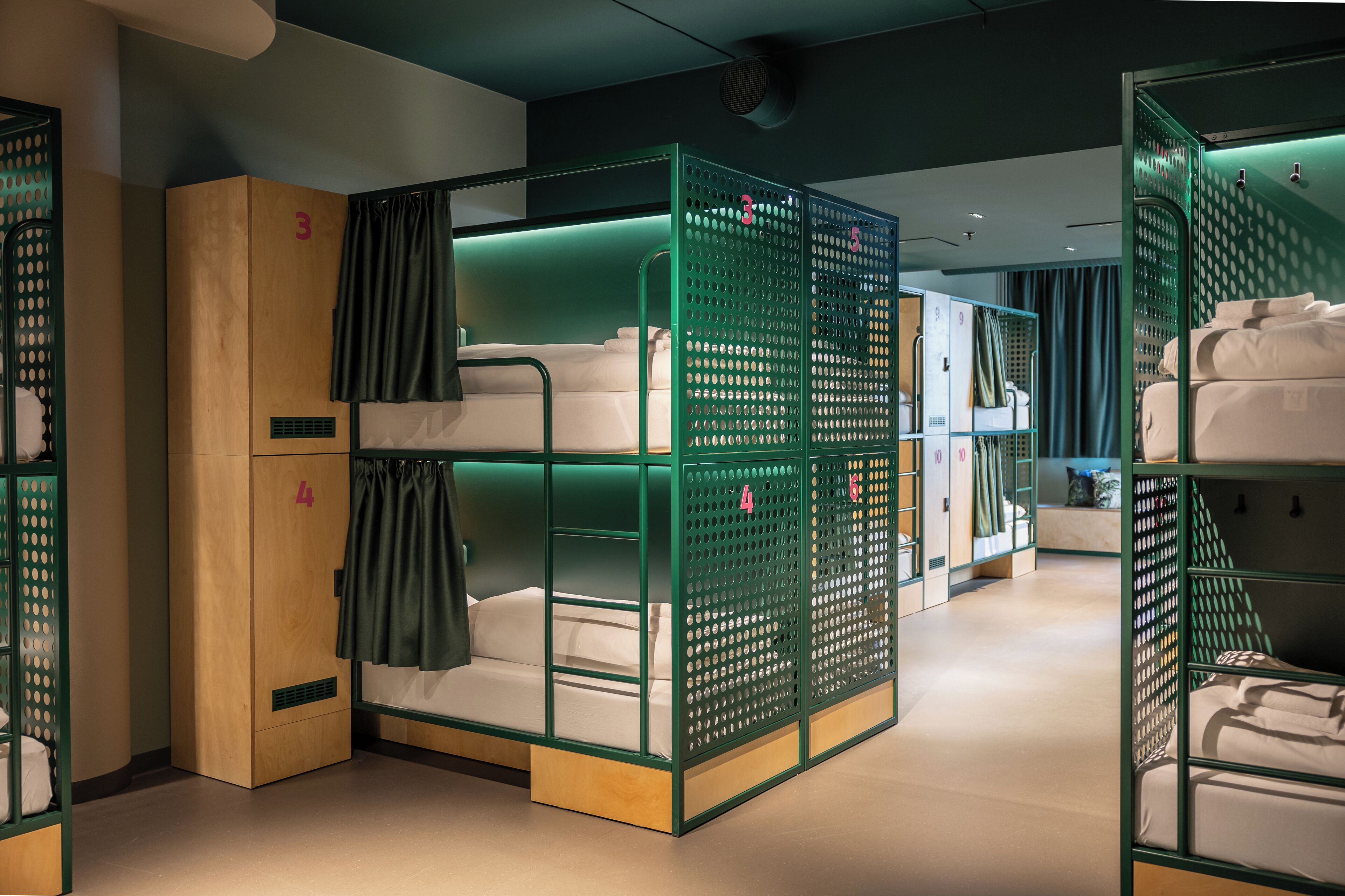 A hotel room with bunk beds, a wardrobe, and a small seating area.