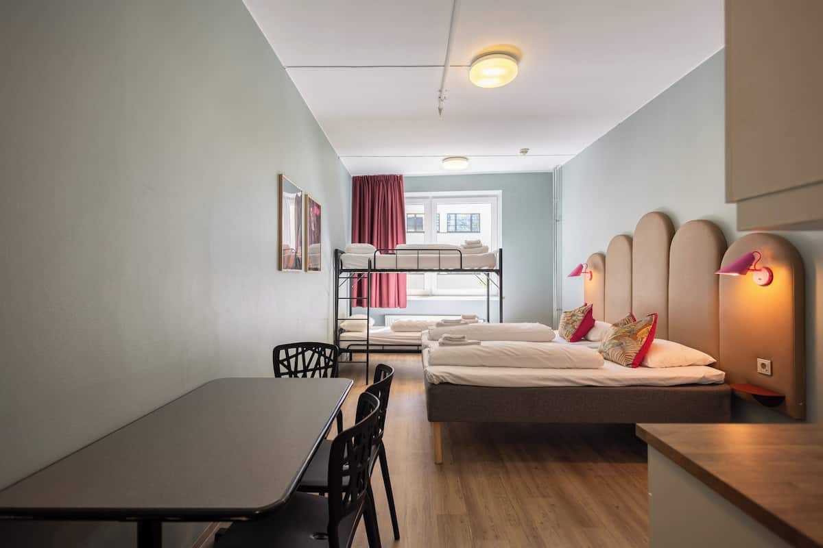 Habitación pequeña con una cama litera, un escritorio y una silla, que cuenta con una ventana con cortinas.