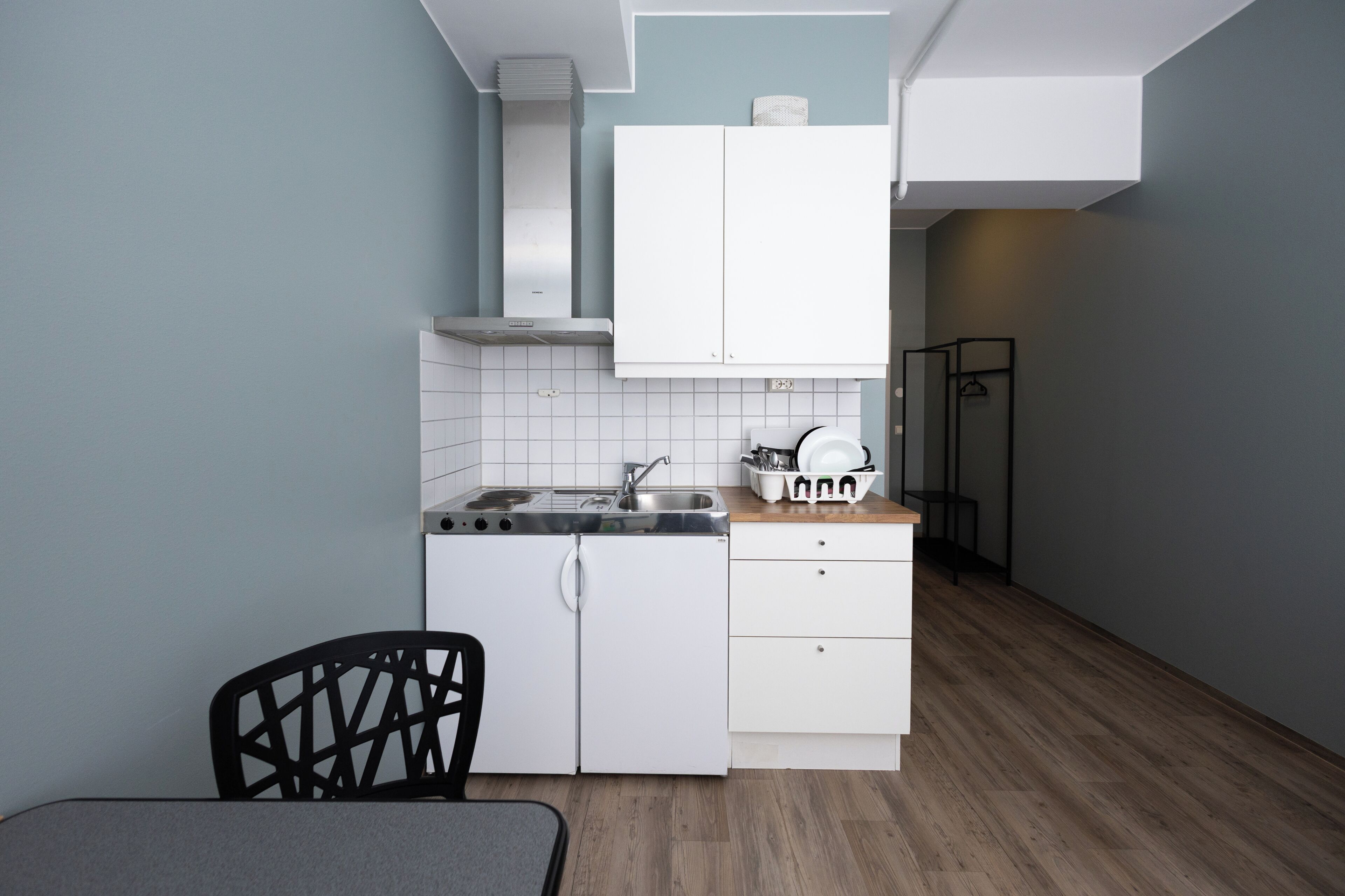 A compact kitchen with white cabinets, a stove, and a sink.