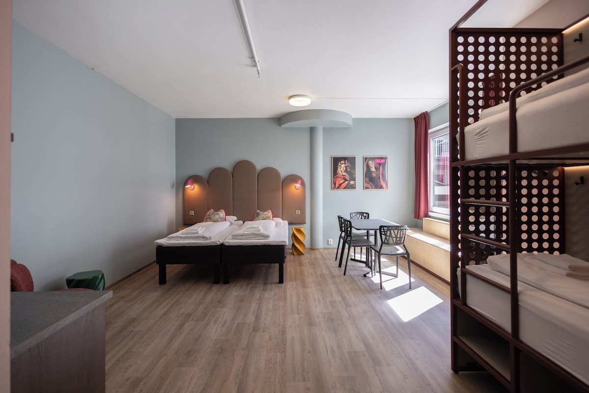 Una habitación de hotel con cama, escritorio, silla, ventana y literas.