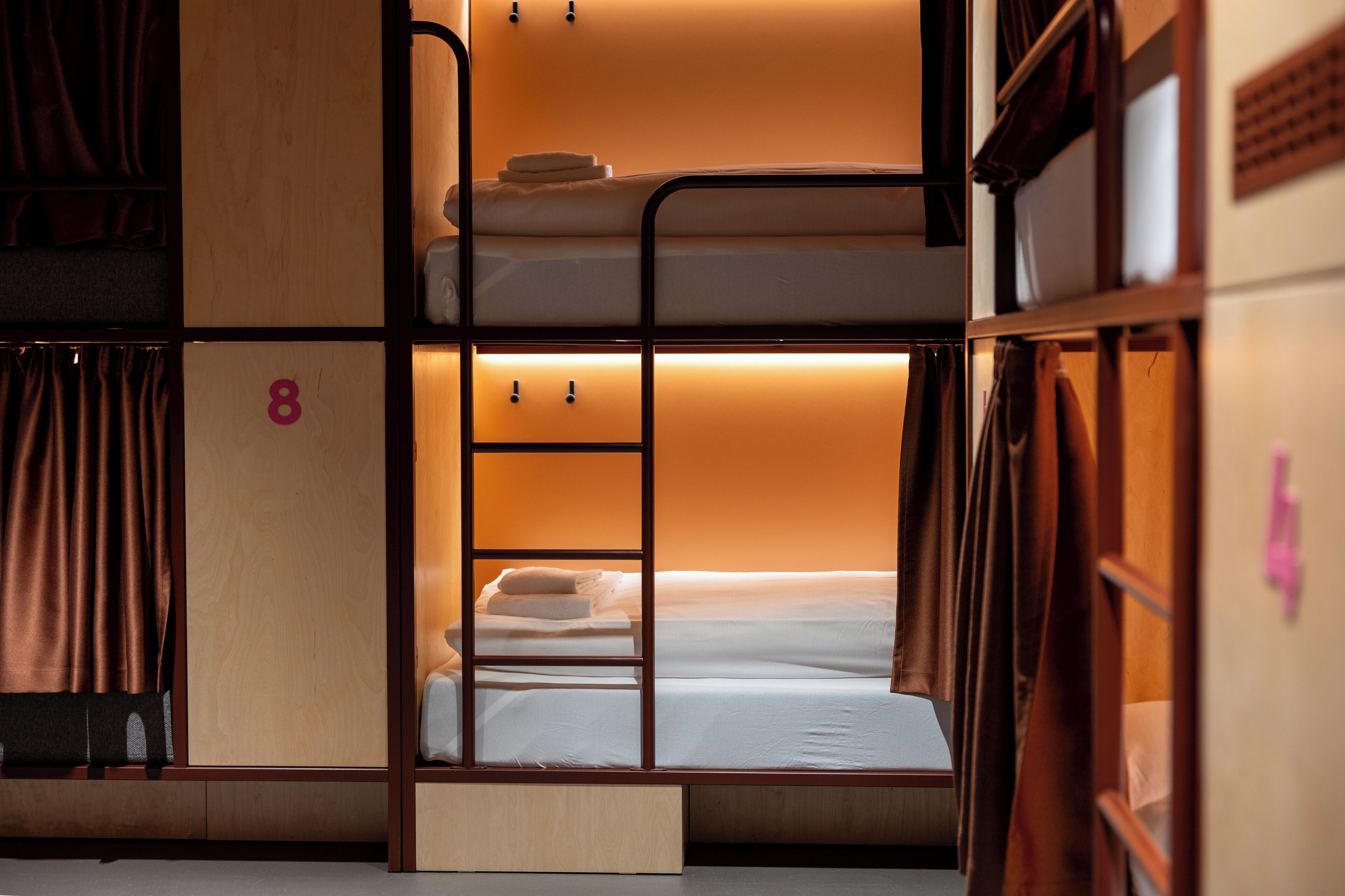 A bunk bed room with a wooden frame, a small desk, and a number '8' on the wall.