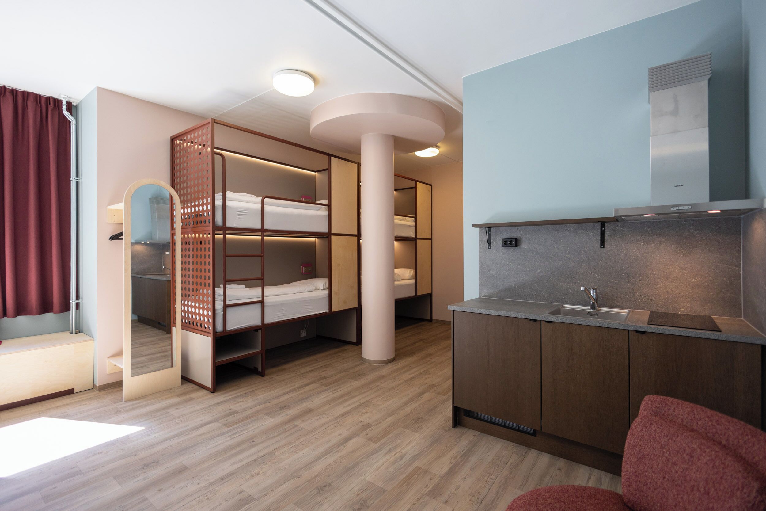 Habitación pequeña con literas, kitchenette y espejo.