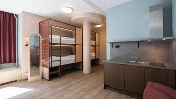 Habitación pequeña con literas, kitchenette y espejo.