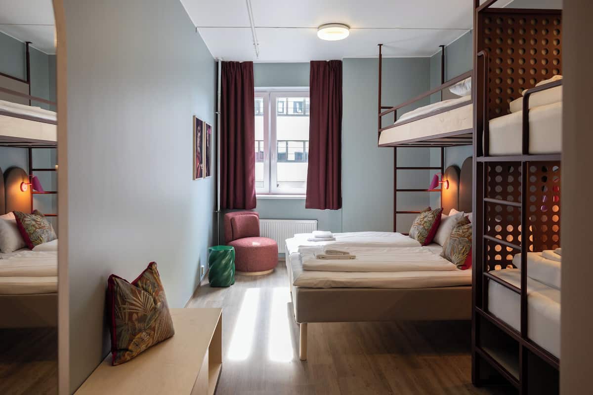 Una habitación con literas, un escritorio, una silla y una ventana con cortinas.