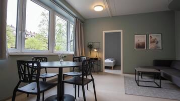 A modern room with a dining table and chairs, a bed, a sofa, and two framed pictures on the wall.