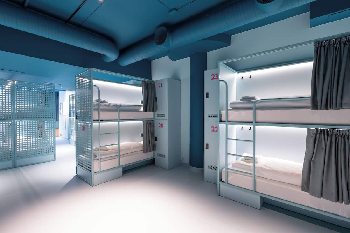 Una habitación de hotel moderna con literas, unidades de almacenamiento numeradas y un sistema de ventilación.