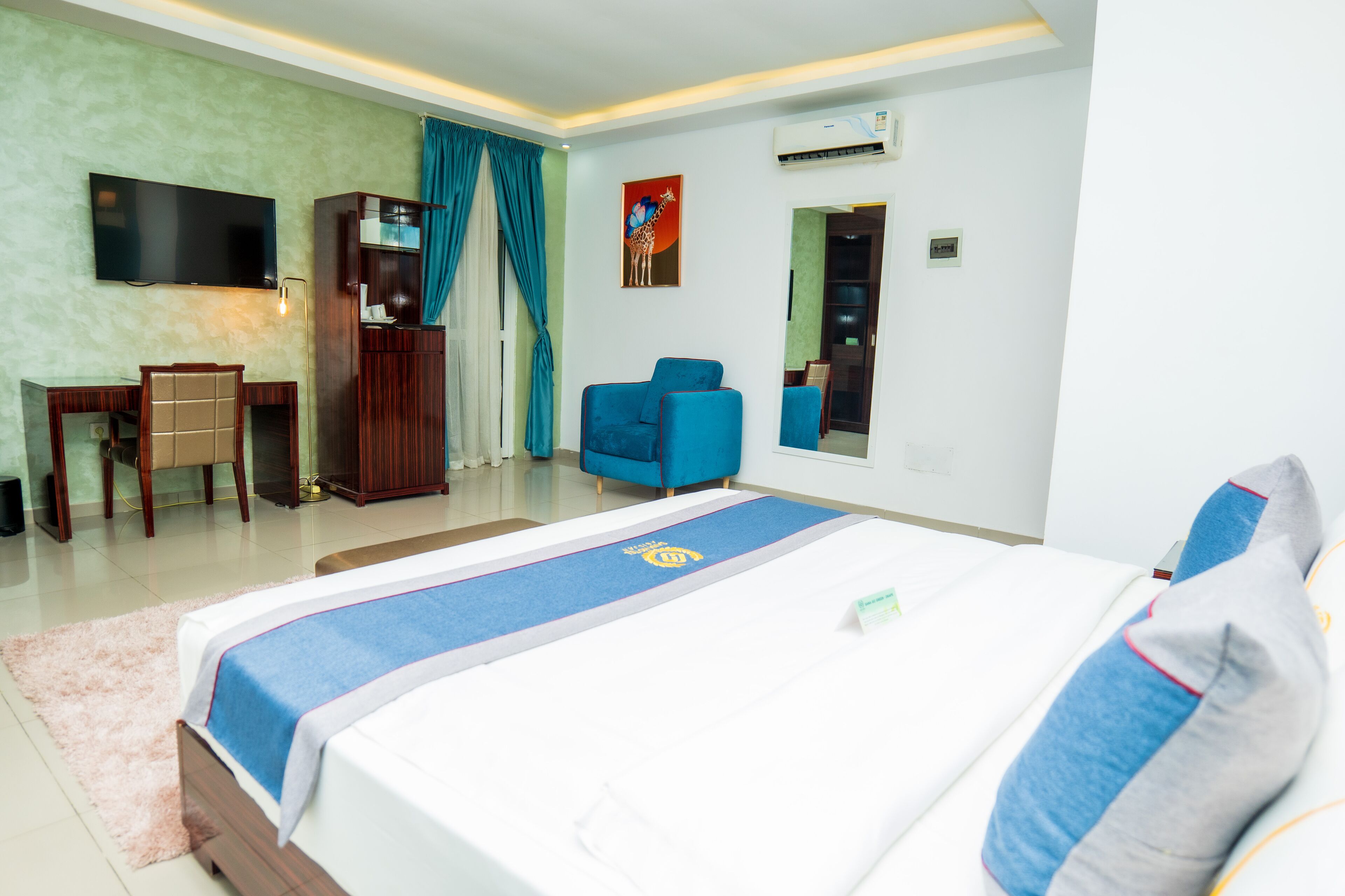 Una habitación de hotel con cama, escritorio, silla, televisión y armario.