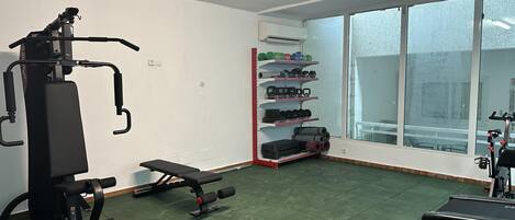 Une salle de sport équipée de machines d’exercice, d’un banc et d’une pile de poids.