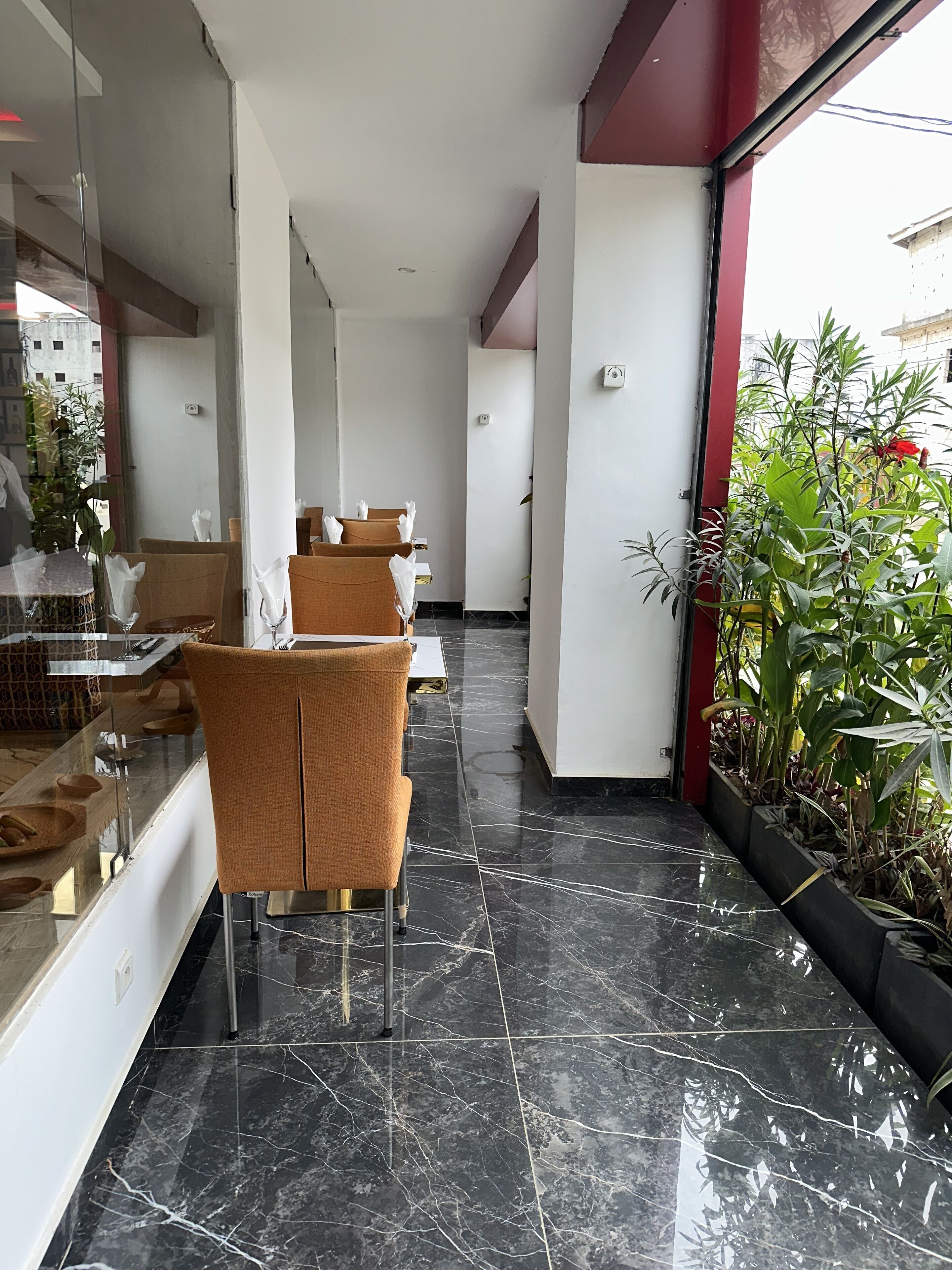 A corridor with a seating area, marble flooring, and potted plants.