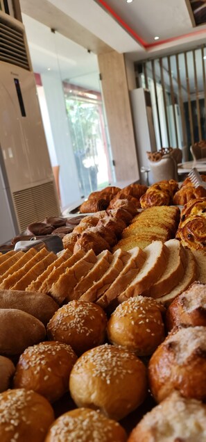 A variety of baked goods including croissants, bread rolls, and pastries displayed in a bakery setting. - Hôtel Sana (Abidjan)