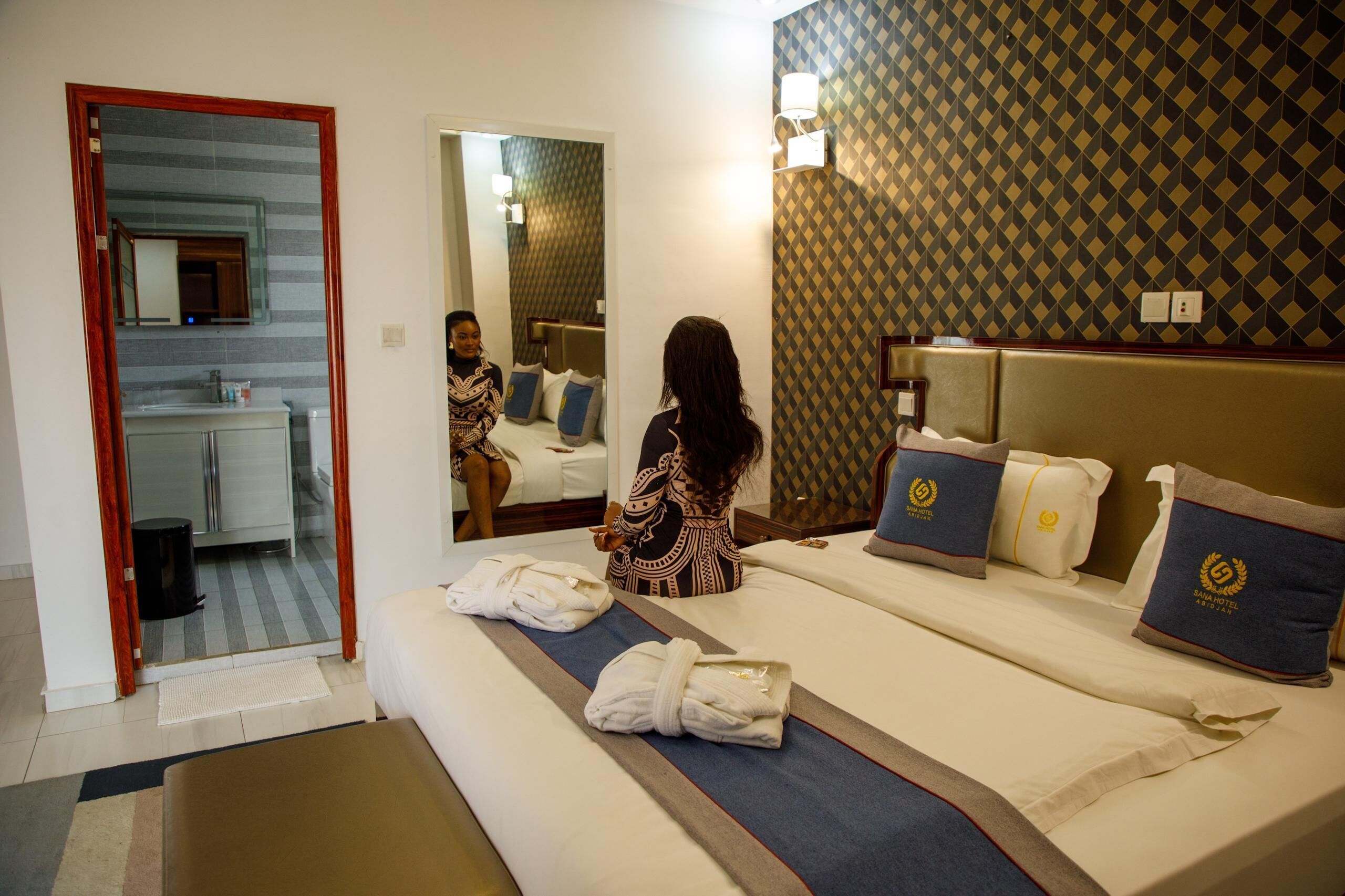 A hotel room with a bed, a bathroom, and a mirror.