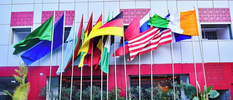 A hotel facade with multiple flags, balconies, and potted plants.