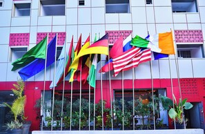 A hotel facade with multiple flags, balconies, and potted plants. - Hôtel Sana (Abidjan)